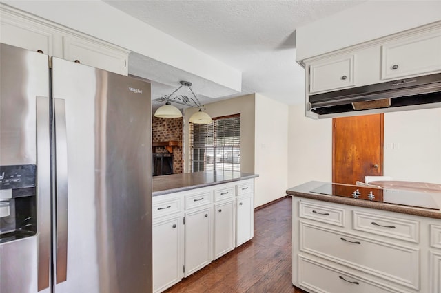 kitchen with white cabinetry, hanging light fixtures, a brick fireplace, dark hardwood / wood-style floors, and stainless steel fridge