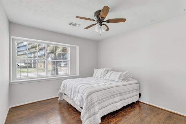 bedroom featuring ceiling fan, dark hardwood / wood-style floors, and a textured ceiling