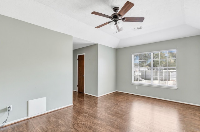 empty room with a textured ceiling, vaulted ceiling, ceiling fan, and dark wood-type flooring