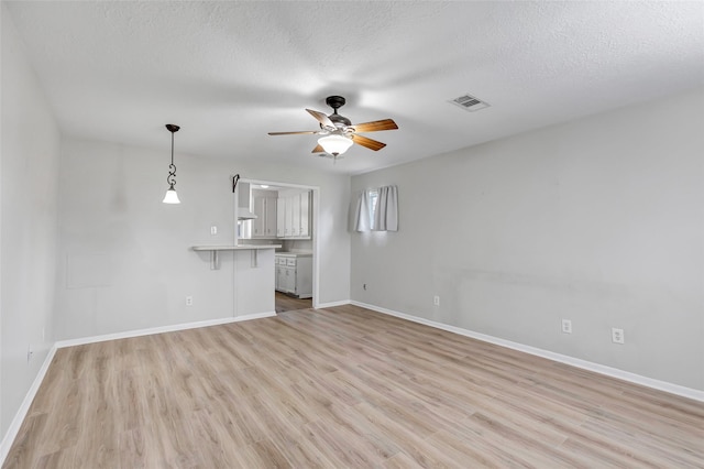 unfurnished living room with a textured ceiling, light hardwood / wood-style flooring, and ceiling fan