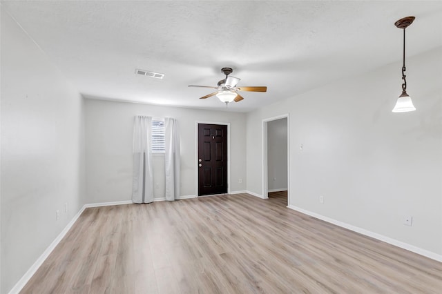 empty room featuring a textured ceiling, light wood-type flooring, and ceiling fan