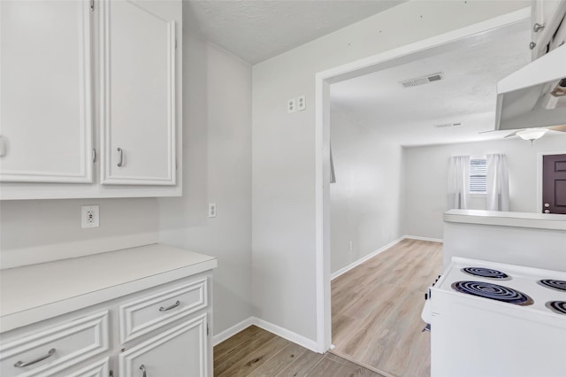 kitchen with white cabinetry, light hardwood / wood-style floors, and white electric stove