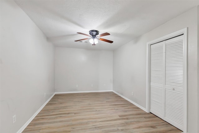 unfurnished bedroom featuring ceiling fan, light wood-type flooring, a textured ceiling, and a closet