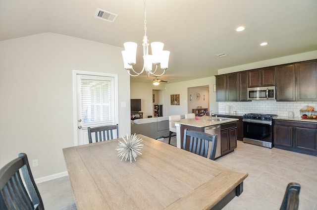 tiled dining room with ceiling fan with notable chandelier, sink, and vaulted ceiling