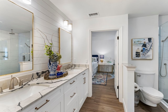 bathroom featuring toilet, wood-type flooring, vanity, and a tile shower