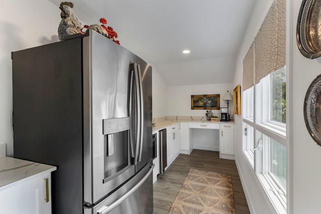 kitchen with vaulted ceiling, stainless steel fridge with ice dispenser, light stone counters, hardwood / wood-style flooring, and white cabinets