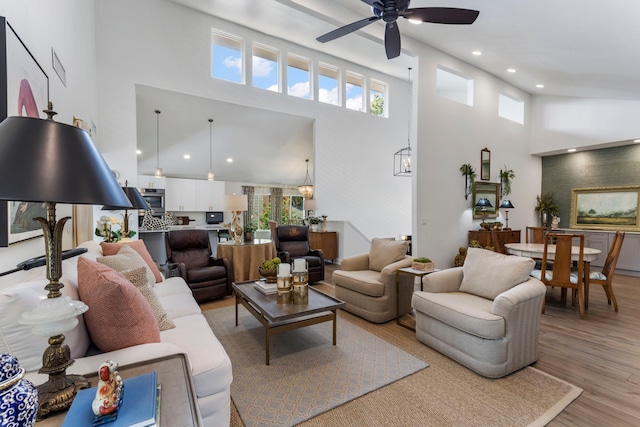 living room featuring a high ceiling, light wood-type flooring, and ceiling fan