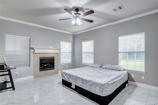 bedroom with ceiling fan, crown molding, and a tiled fireplace