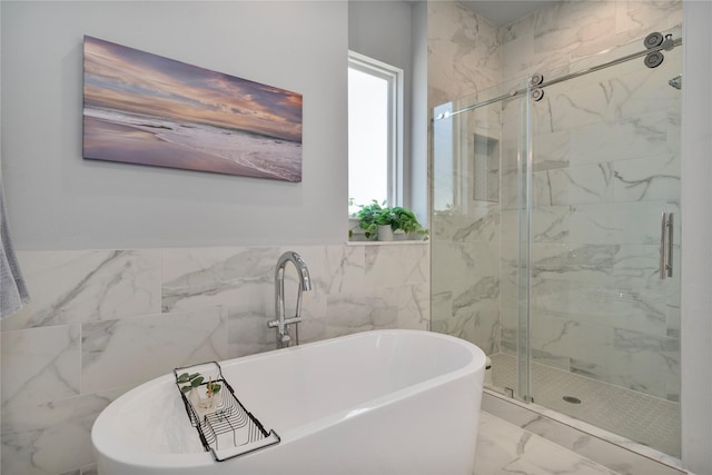 bathroom with shower with separate bathtub and tile walls