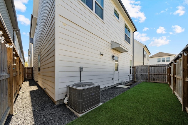 exterior space featuring central air condition unit and a lawn