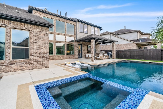 view of pool with an in ground hot tub, a patio, and area for grilling