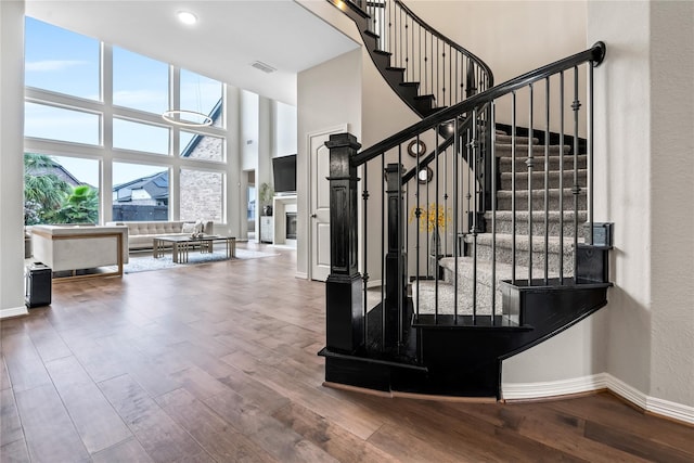 staircase with hardwood / wood-style floors and a high ceiling