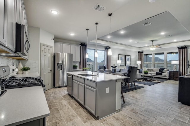 kitchen featuring ceiling fan, sink, an island with sink, pendant lighting, and appliances with stainless steel finishes