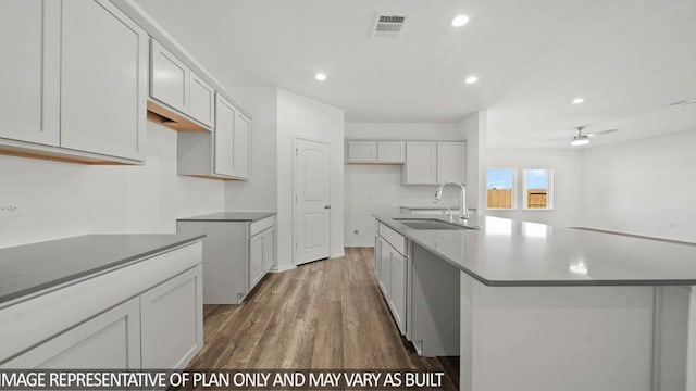 kitchen with sink, white cabinetry, a kitchen island with sink, and dark wood-type flooring