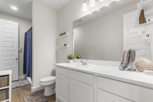 bathroom with wood-type flooring, vanity, toilet, and curtained shower