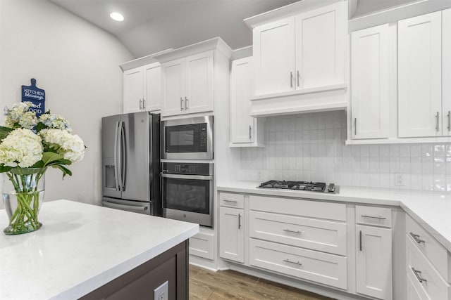 kitchen with white cabinets, dark hardwood / wood-style floors, appliances with stainless steel finishes, and tasteful backsplash