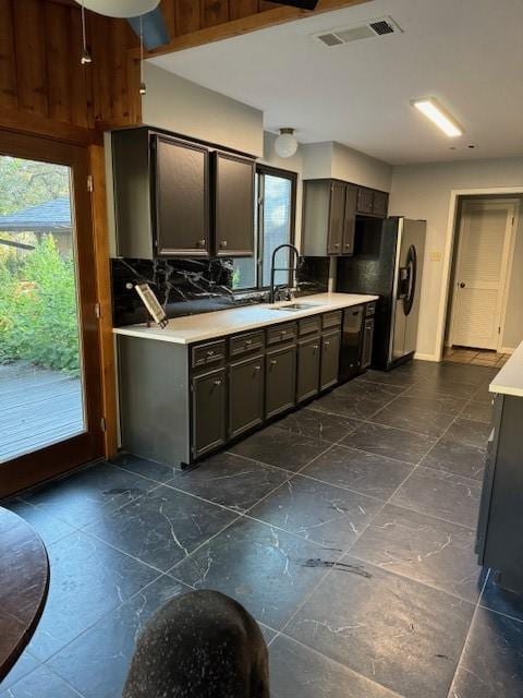 kitchen featuring black dishwasher, stainless steel fridge with ice dispenser, dark brown cabinetry, and sink