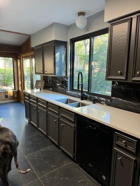 kitchen with dishwasher, sink, wooden walls, vaulted ceiling, and tasteful backsplash