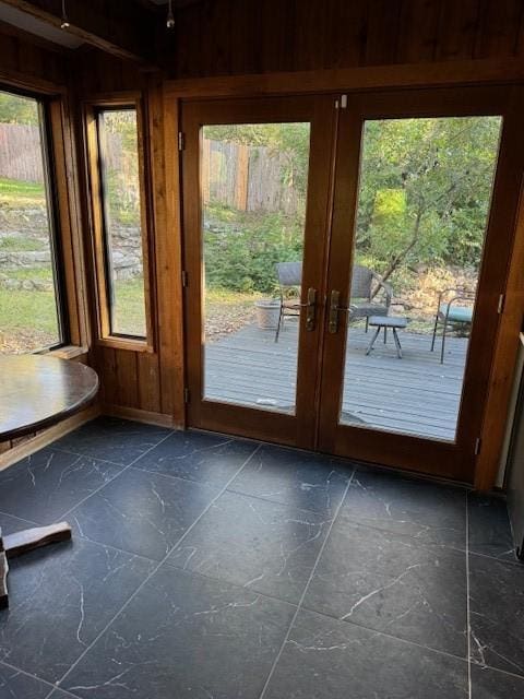 entryway featuring a wealth of natural light, wooden walls, and french doors