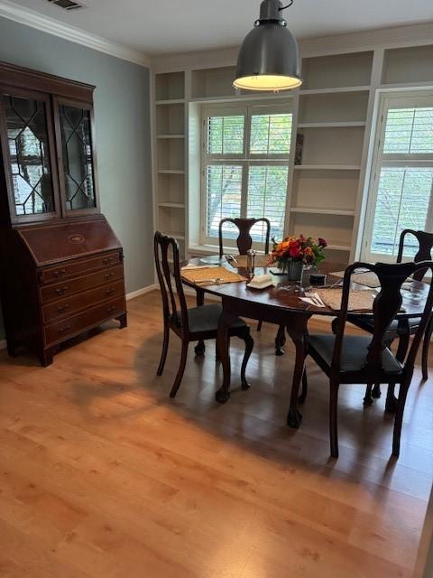 dining room with built in features, hardwood / wood-style floors, and ornamental molding