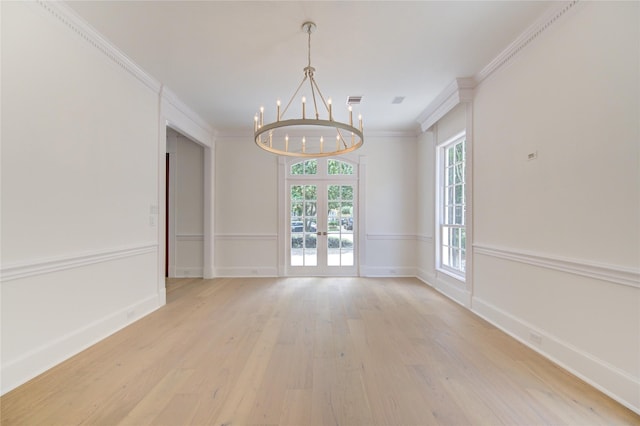 unfurnished room featuring a notable chandelier, light hardwood / wood-style floors, ornamental molding, and french doors