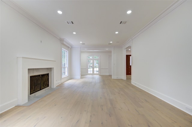 unfurnished living room featuring french doors, light hardwood / wood-style floors, crown molding, and a tiled fireplace