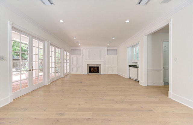 unfurnished living room featuring light hardwood / wood-style floors, crown molding, and french doors