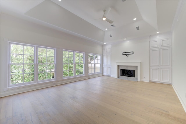 unfurnished living room featuring ceiling fan, a fireplace, a towering ceiling, and a healthy amount of sunlight