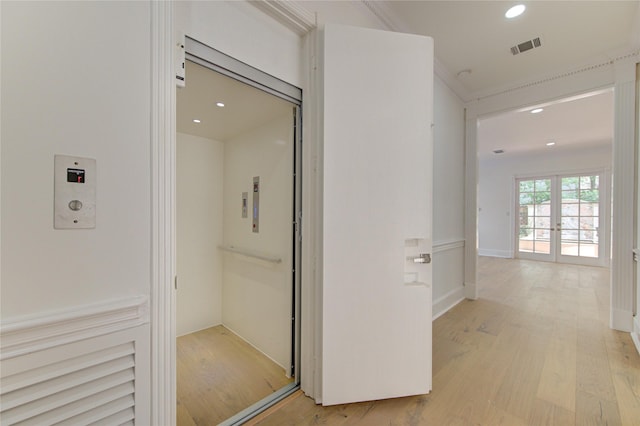 hall with crown molding, light hardwood / wood-style flooring, elevator, and french doors