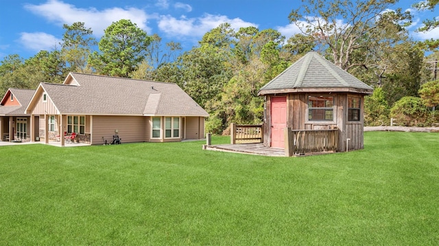 rear view of property featuring roof with shingles, a yard, and a patio