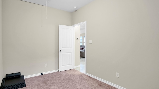 empty room featuring attic access, carpet, and baseboards