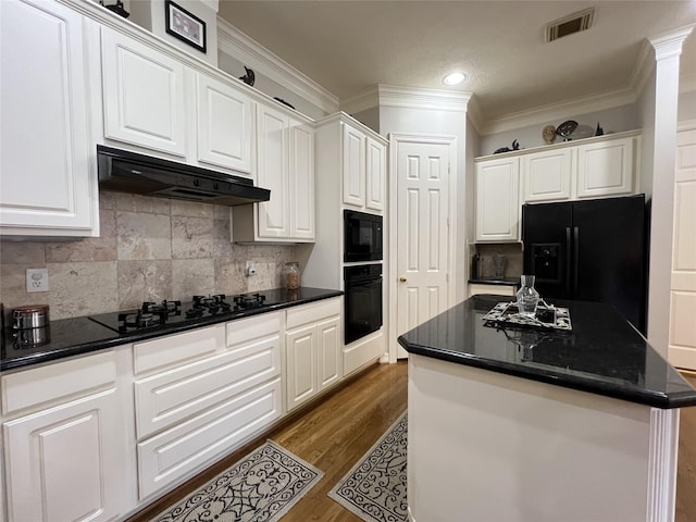 kitchen with dark wood-type flooring, crown molding, black appliances, a center island, and white cabinetry