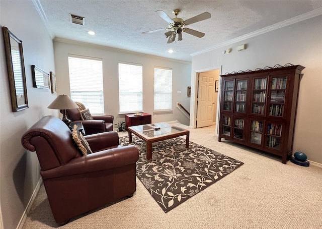 living room featuring a textured ceiling, ceiling fan, crown molding, and light carpet