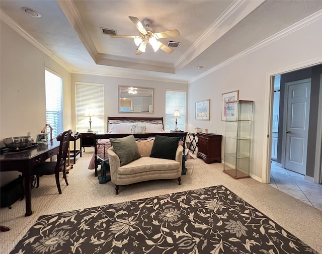 carpeted bedroom with a tray ceiling, ceiling fan, and ornamental molding