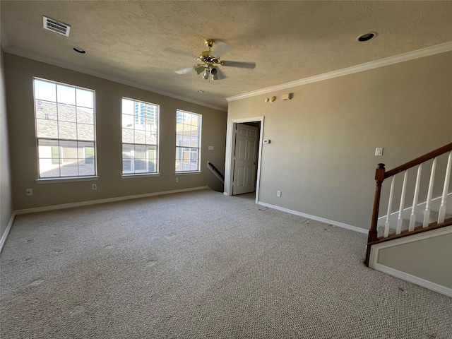 empty room with ceiling fan, light colored carpet, a textured ceiling, and ornamental molding