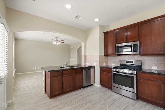 kitchen with backsplash, sink, ceiling fan, appliances with stainless steel finishes, and kitchen peninsula