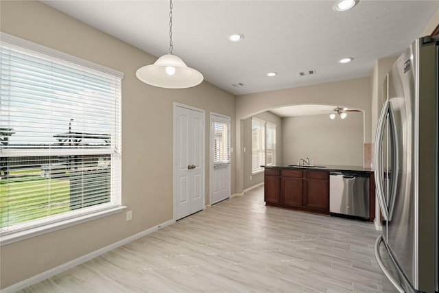 kitchen with pendant lighting, sink, ceiling fan, light wood-type flooring, and appliances with stainless steel finishes