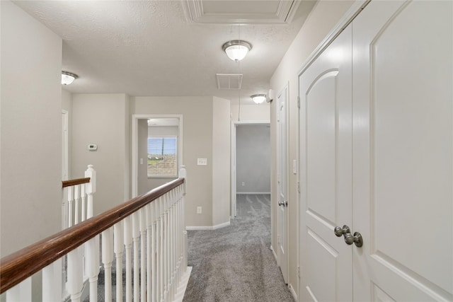 hallway with light carpet and a textured ceiling