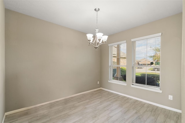 spare room with light hardwood / wood-style flooring and a chandelier