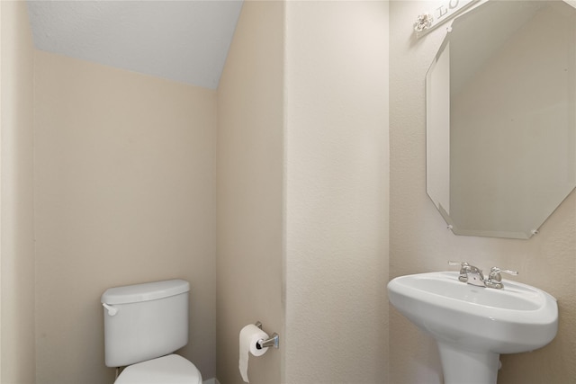 bathroom with toilet, lofted ceiling, and sink