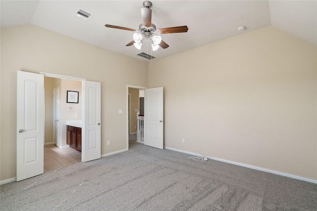 unfurnished bedroom with ceiling fan, light colored carpet, connected bathroom, and vaulted ceiling