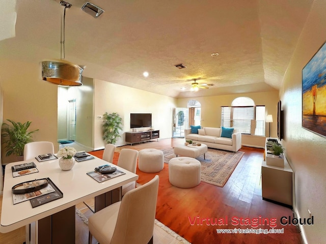 living room featuring wood-type flooring, vaulted ceiling, ceiling fan, and a textured ceiling