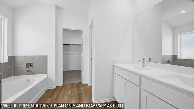 bathroom featuring vanity, a bath, vaulted ceiling, and hardwood / wood-style flooring