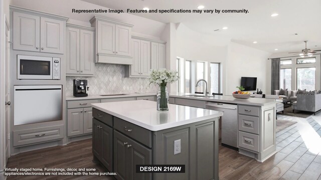 kitchen with stainless steel dishwasher, white microwave, sink, gray cabinets, and a kitchen island