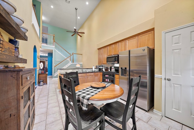 kitchen with high vaulted ceiling, ceiling fan, light tile patterned floors, and appliances with stainless steel finishes