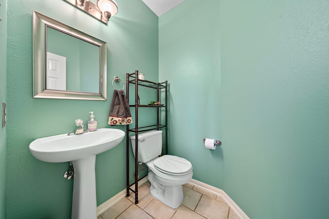 bathroom with toilet, tile patterned floors, and sink