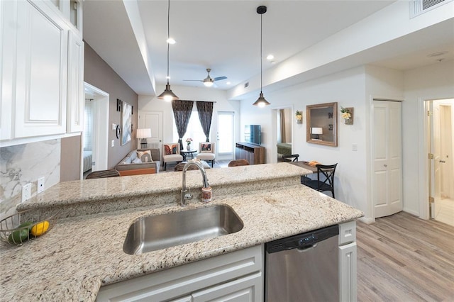 kitchen with stainless steel dishwasher, white cabinets, sink, and hanging light fixtures