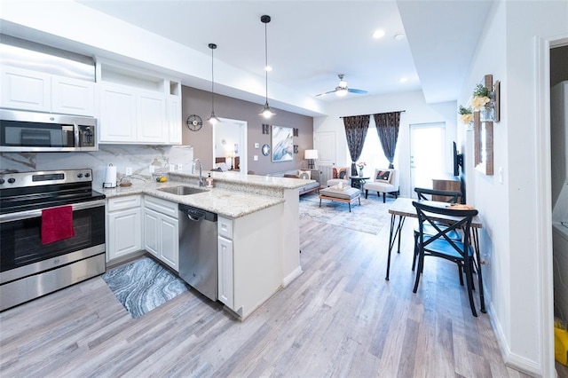 kitchen featuring backsplash, sink, ceiling fan, appliances with stainless steel finishes, and white cabinetry