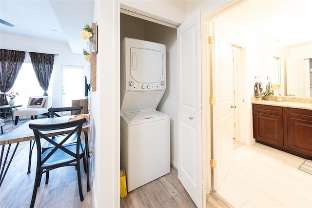 washroom with stacked washing maching and dryer and light hardwood / wood-style floors