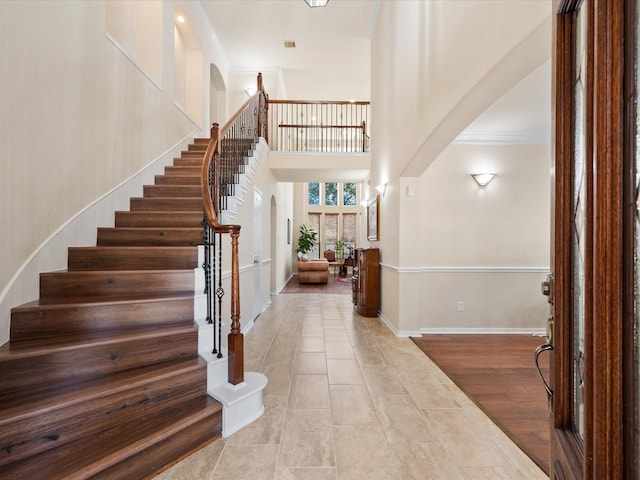 tiled foyer with ornamental molding and a high ceiling